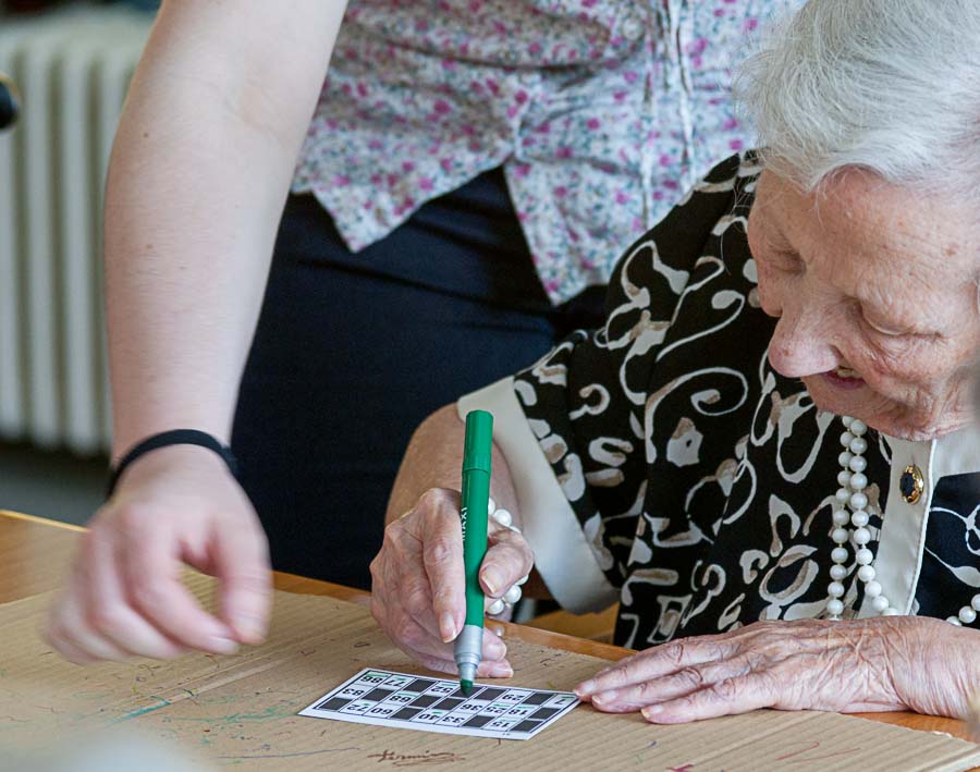  egoiliar batek bingo-txartel bat betetzen du laguntzaile baten laguntzaz
